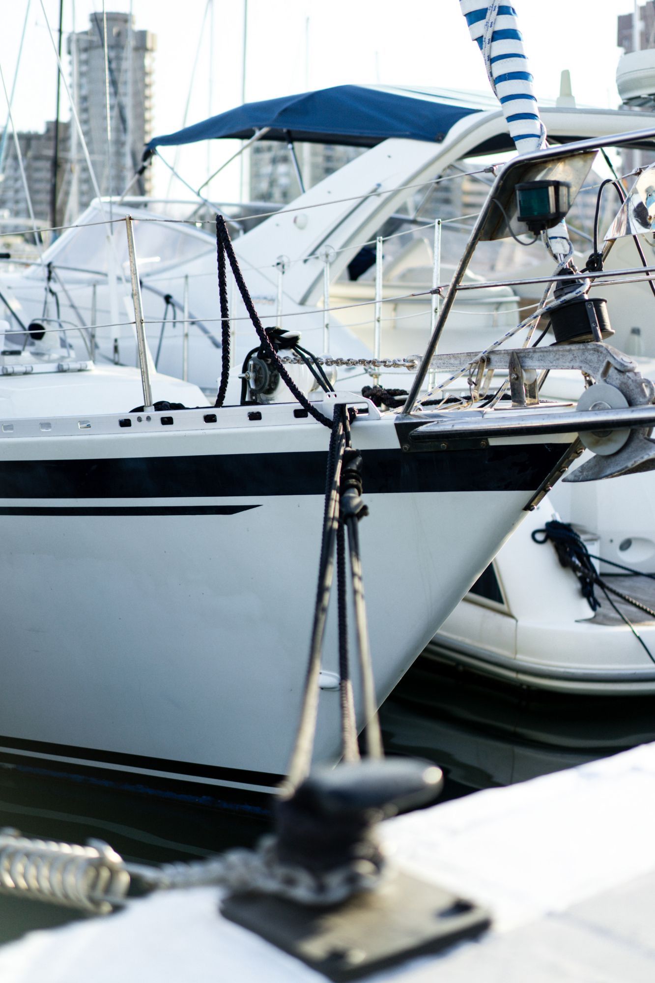 White sailboat docked in a marina, with blue canopy and rigging visible.