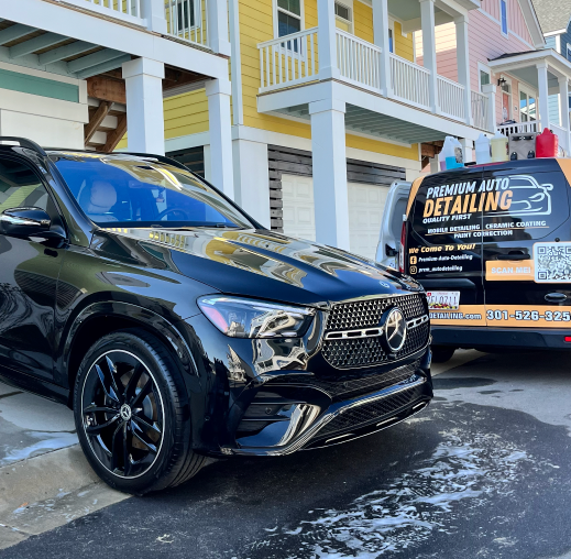 Black SUV parked outside colorful houses beside a mobile window tinting van.