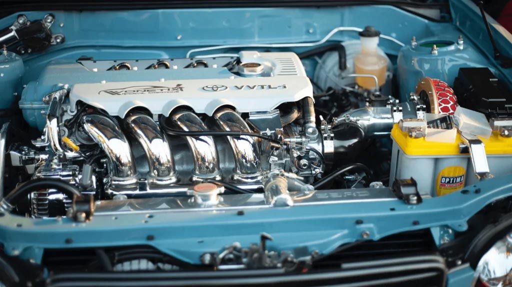 Chrome engine in a blue car bay, with polished intake runners and yellow battery compartment