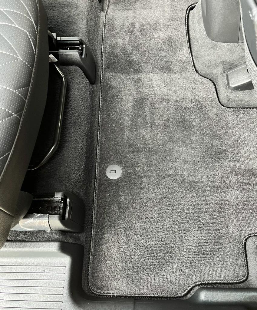 Car trunk floor with black seat edge and gray carpeted mat