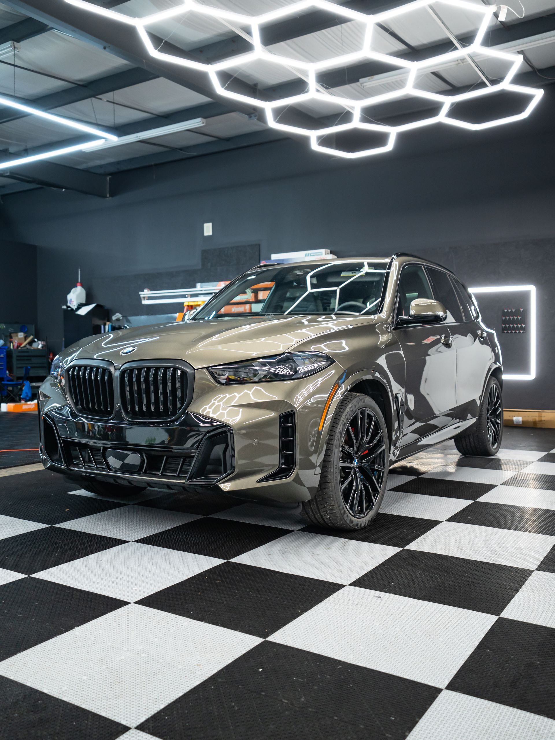 Gray BMW SUV in a modern showroom with hexagonal ceiling lights and checkered floor