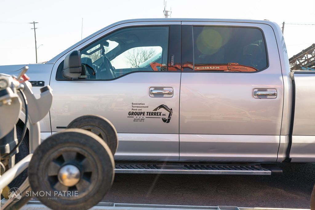 Un camion argenté est garé dans un parking à côté d'une remorque.