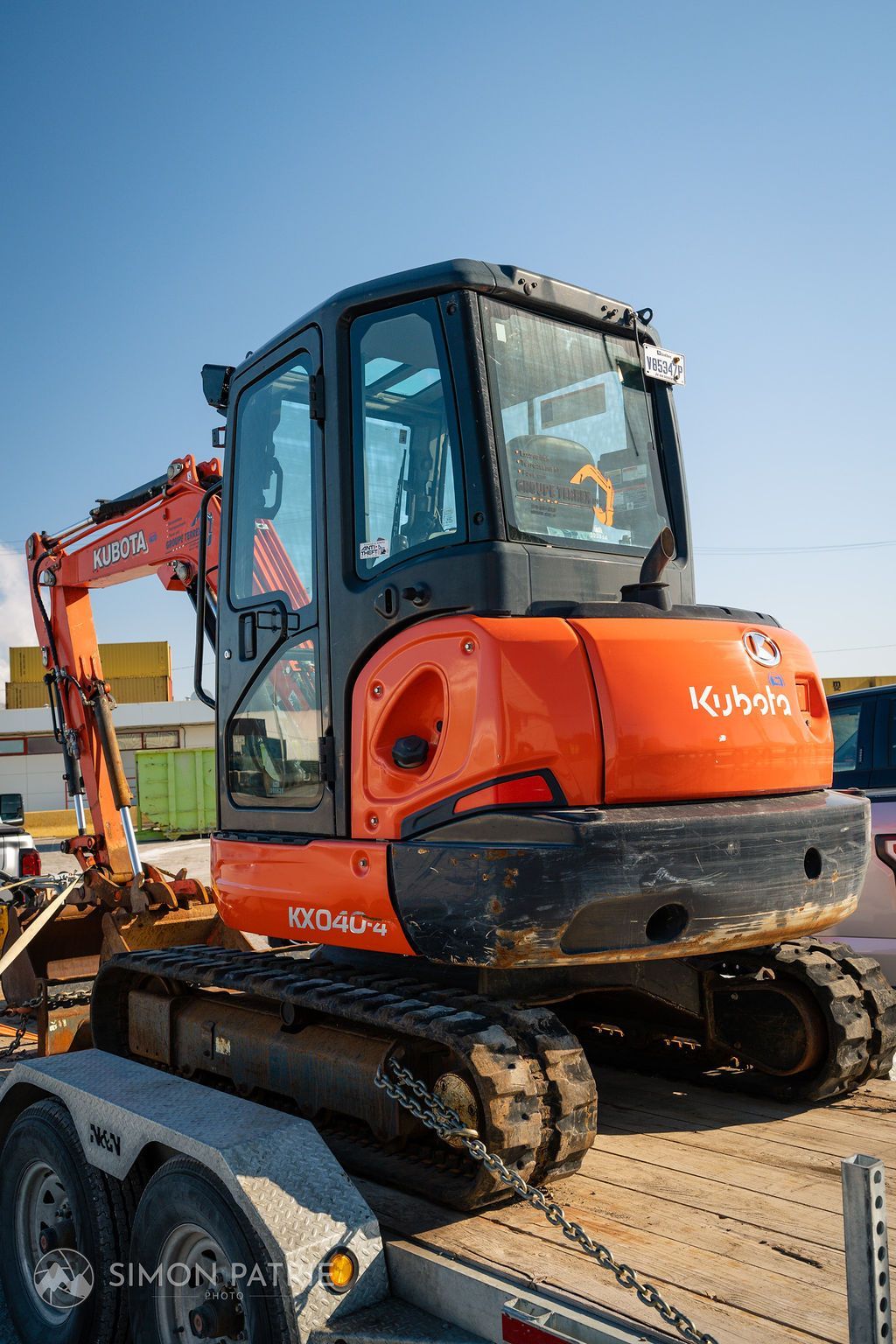 Une petite pelle orange est garée au sommet d'une remorque.