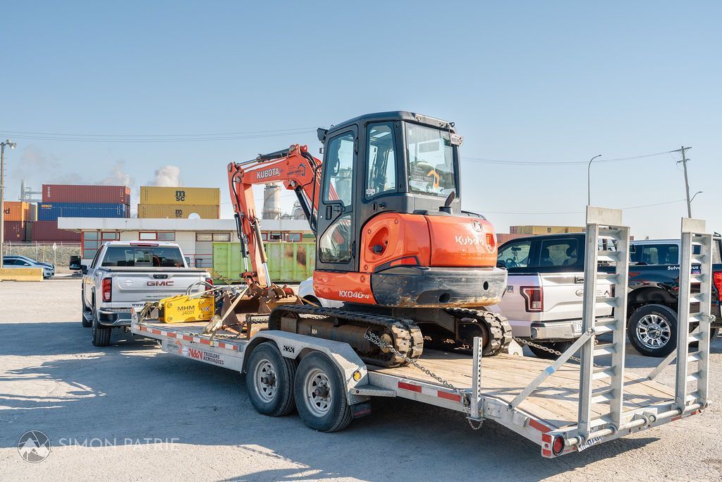 Un camion remorque une petite pelle sur une remorque.