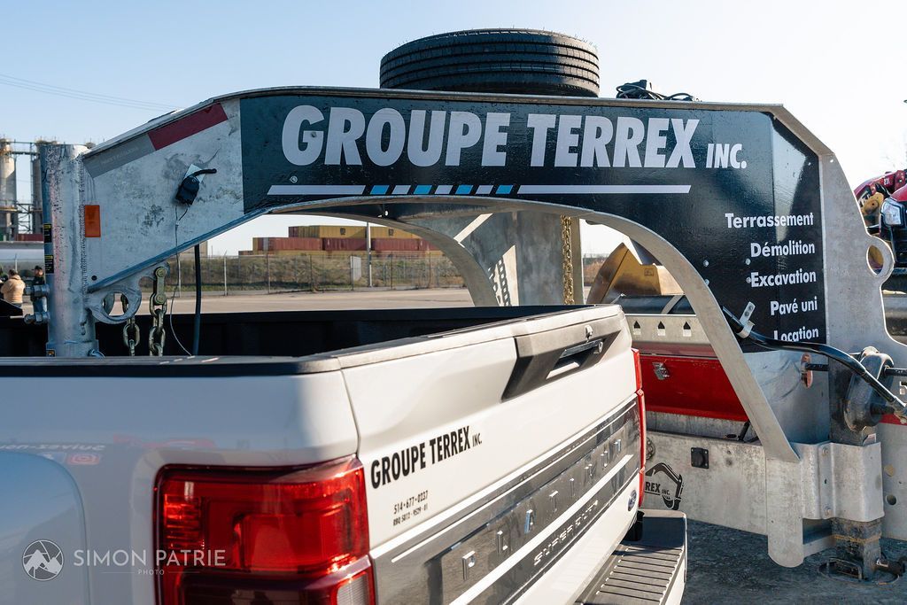 Un camion blanc auquel est attachée une remorque est garé sur le bord de la route.