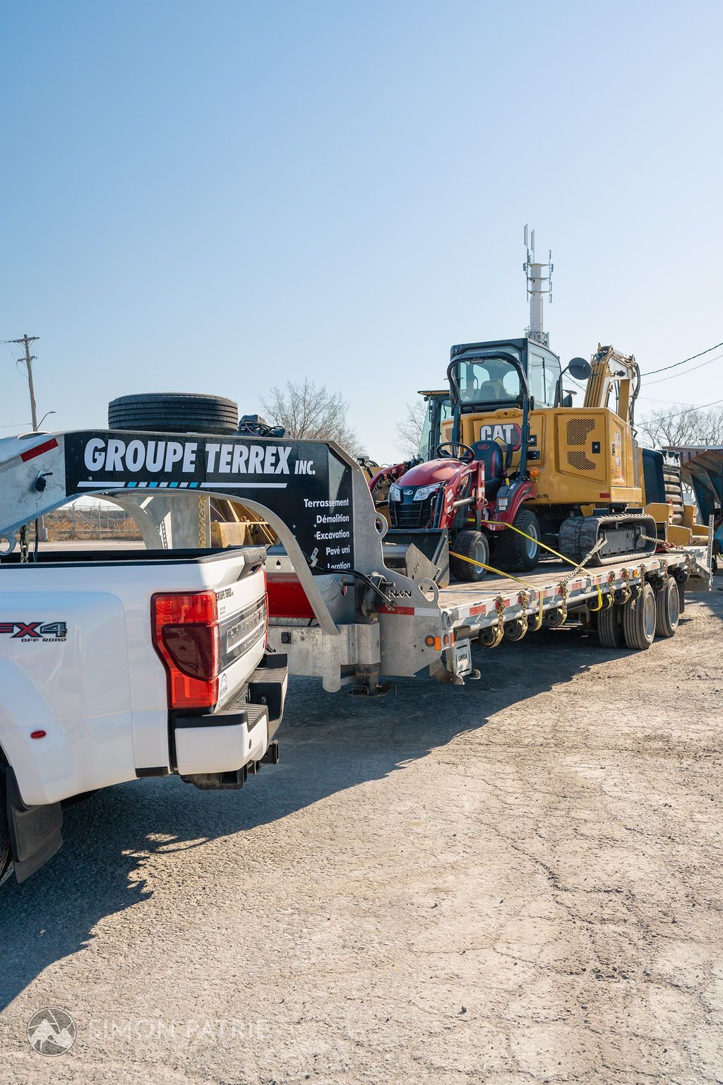 Un camion tire une remorque avec un bulldozer dessus.