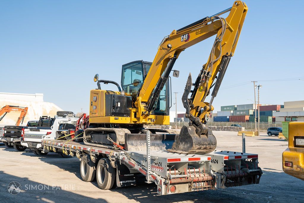 Une excavatrice jaune est assise au sommet d'une remorque à plateau.