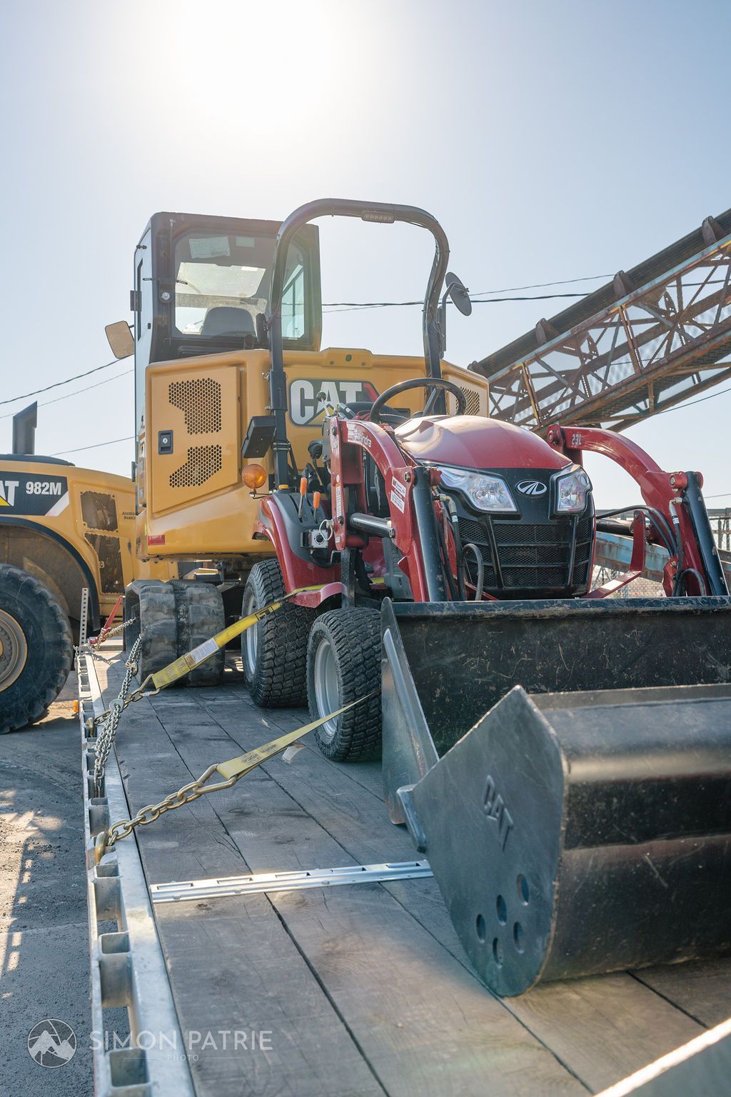 Un tracteur est assis au sommet d'une plate-forme en bois à côté d'un bulldozer.