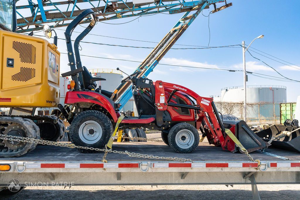 Un tracteur rouge est assis sur un camion à plateau.
