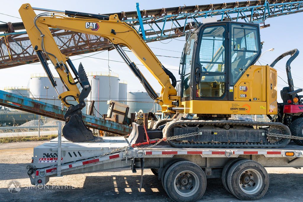 Une pelle jaune est assise au sommet d'une remorque.
