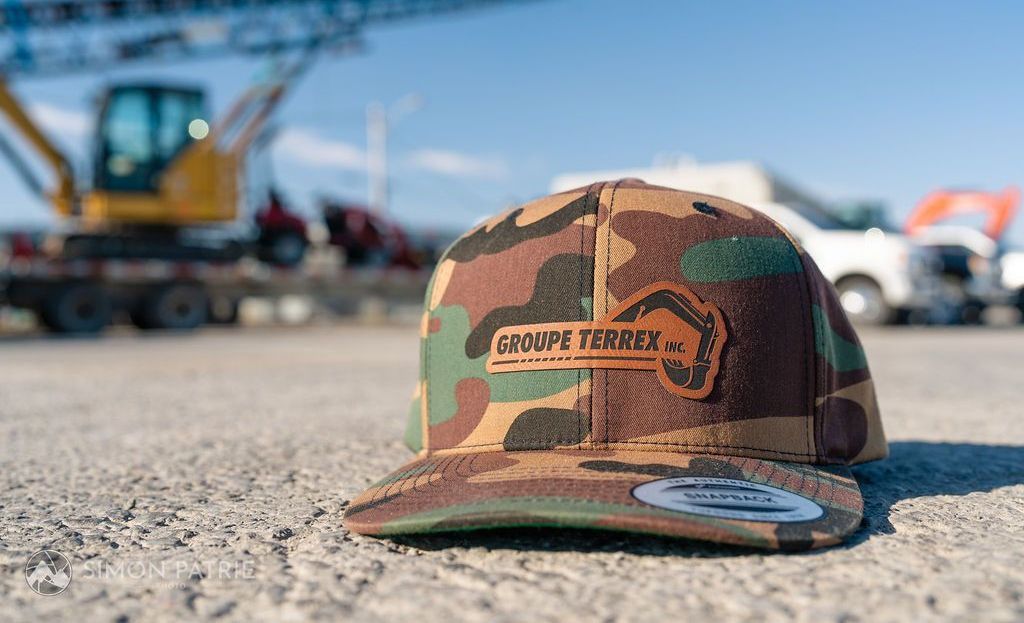 Une casquette de baseball camouflage est posée sur le sol devant un chantier de construction.