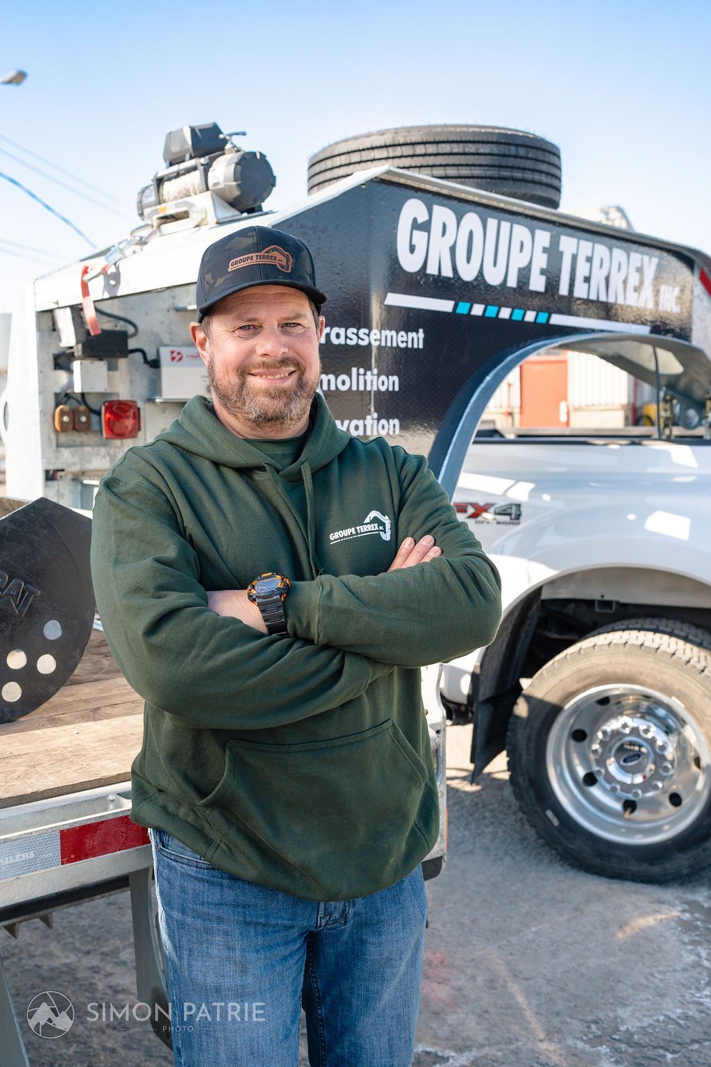 Un homme se tient devant un camion, les bras croisés.