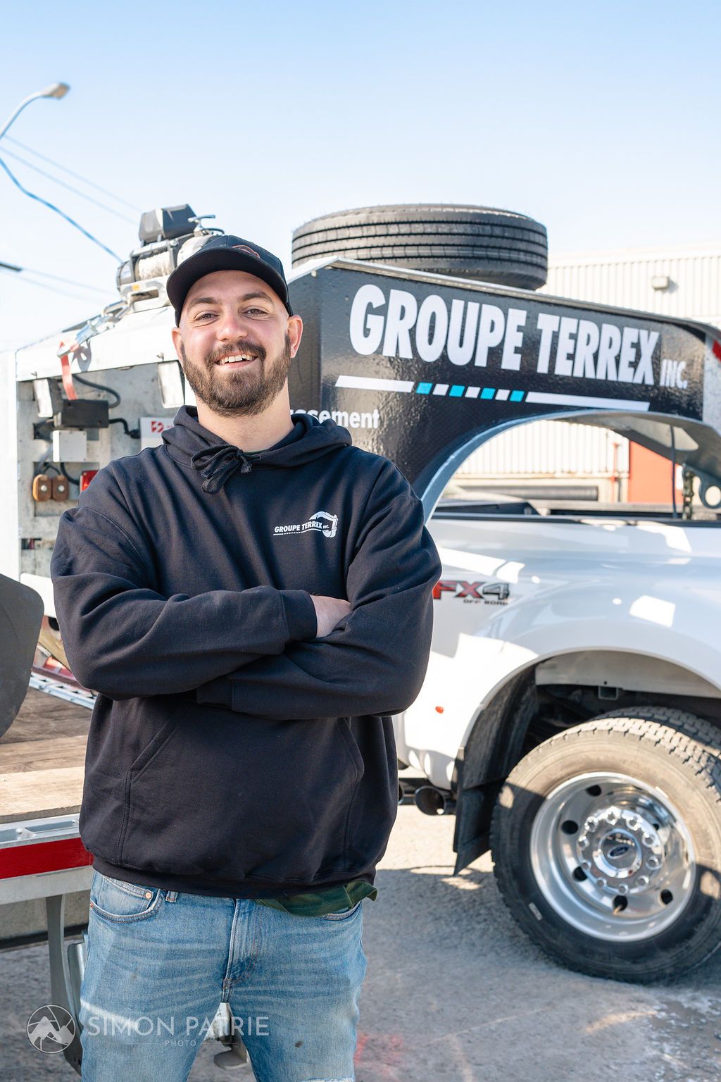 Un homme se tient devant un camion, les bras croisés.