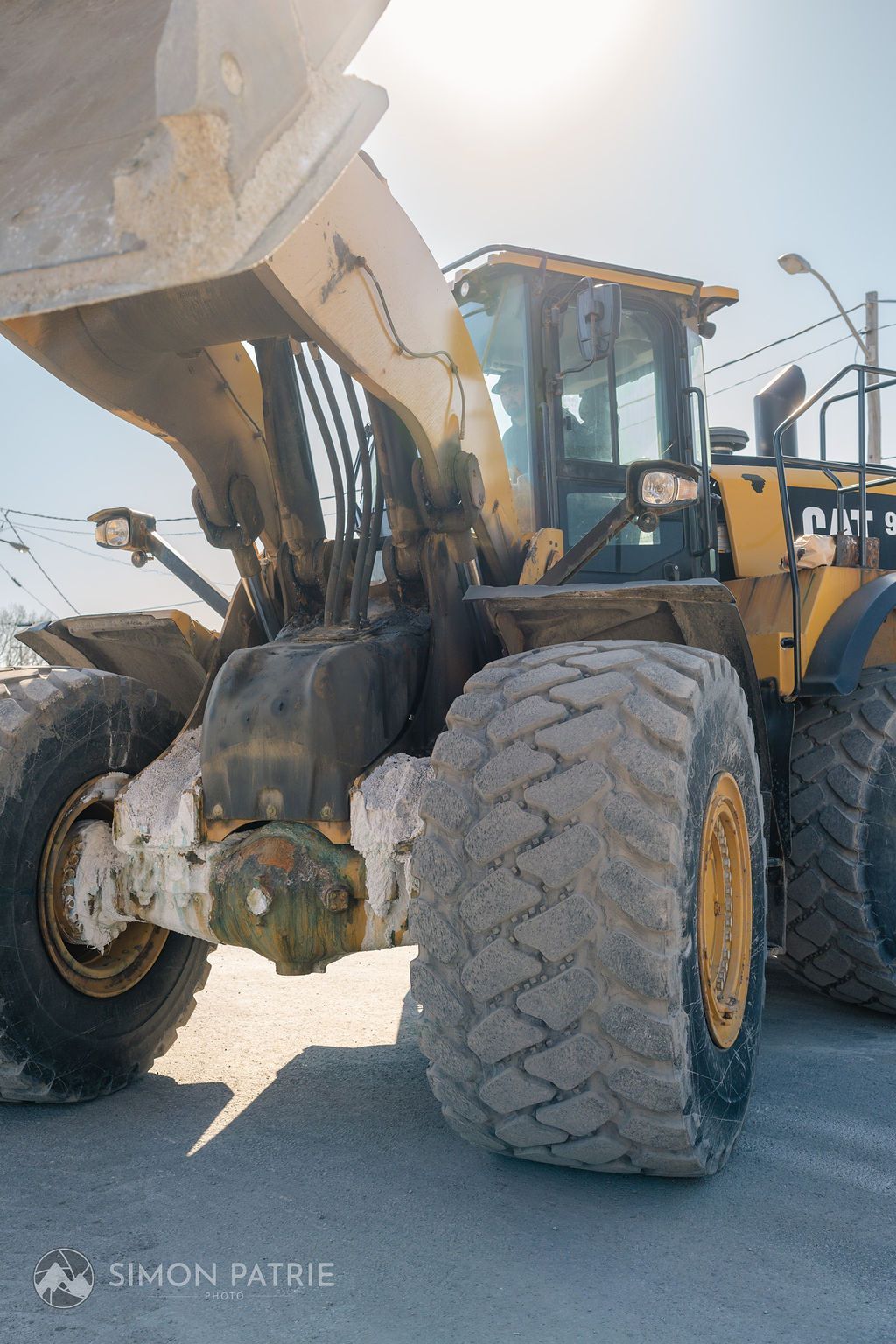 Un bulldozer jaune et blanc est garé sur le bord de la route.