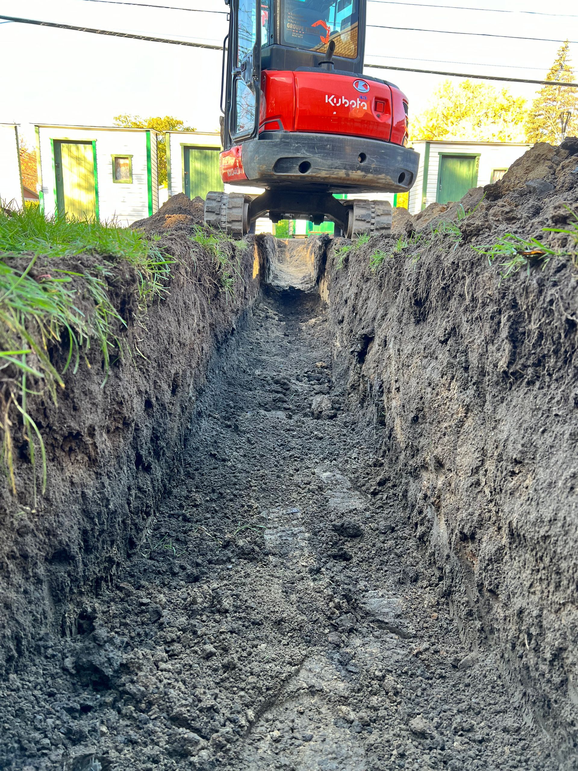 Une excavatrice rouge creuse un trou dans la terre.