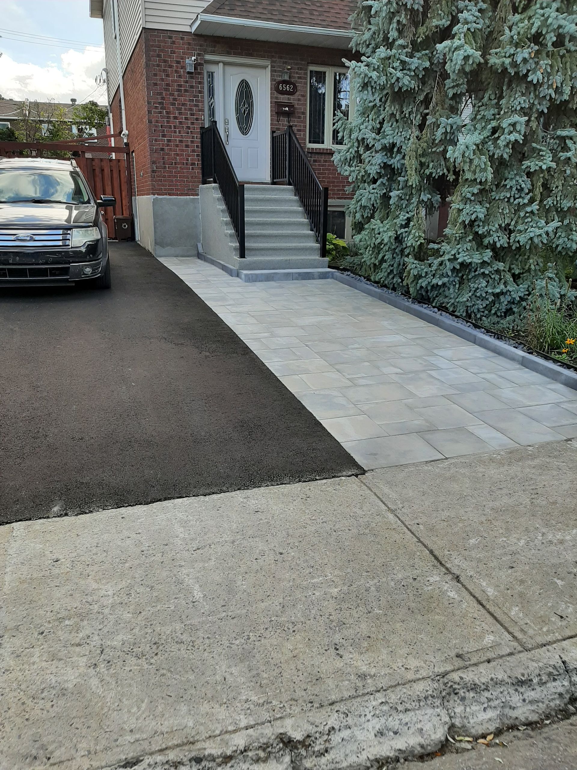 Une voiture est garée devant une maison avec des escaliers qui y mènent.