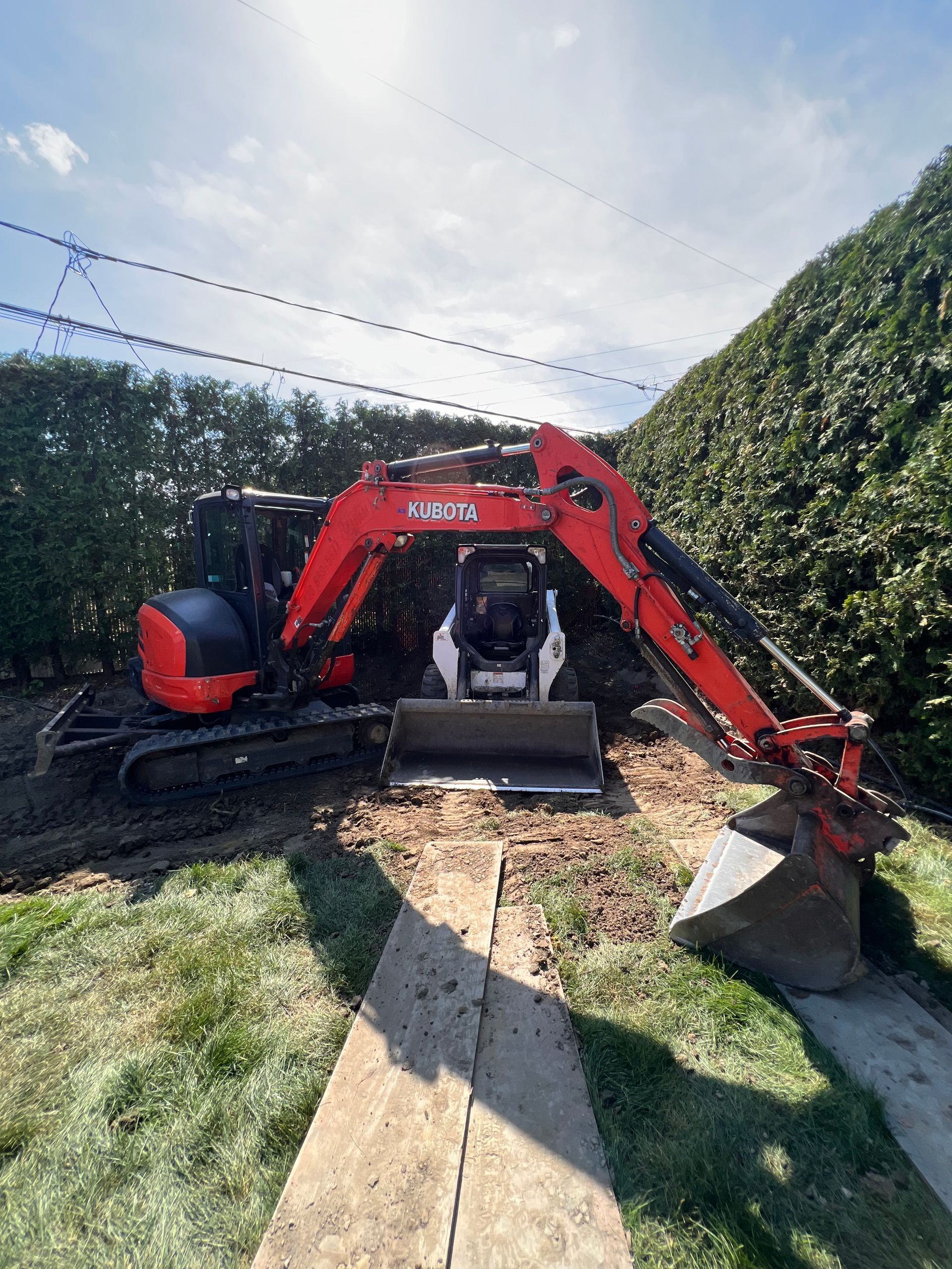 Une excavatrice rouge et noire est assise sur un champ couvert d'herbe.