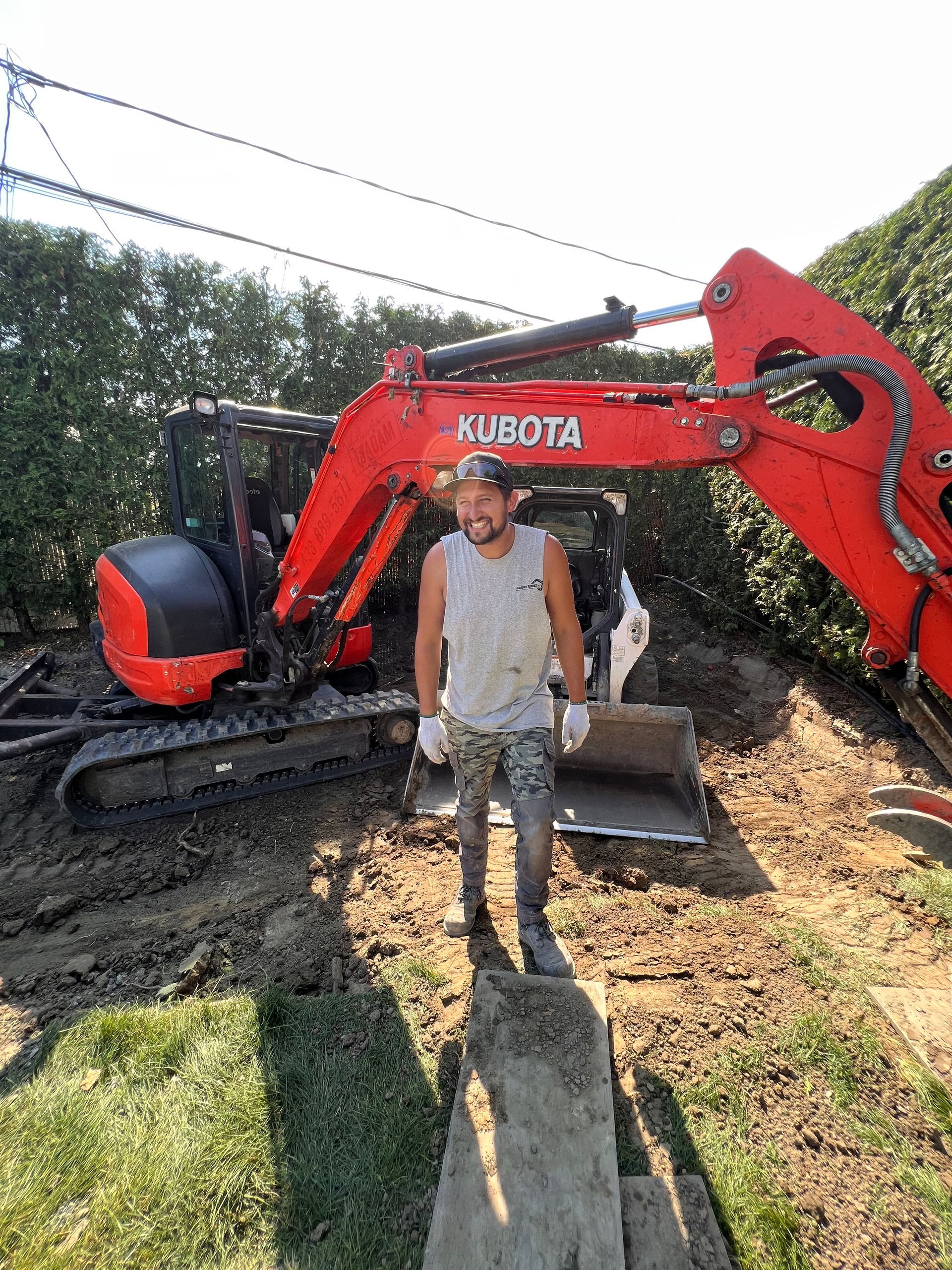 Un homme se tient devant une excavatrice dans la terre.