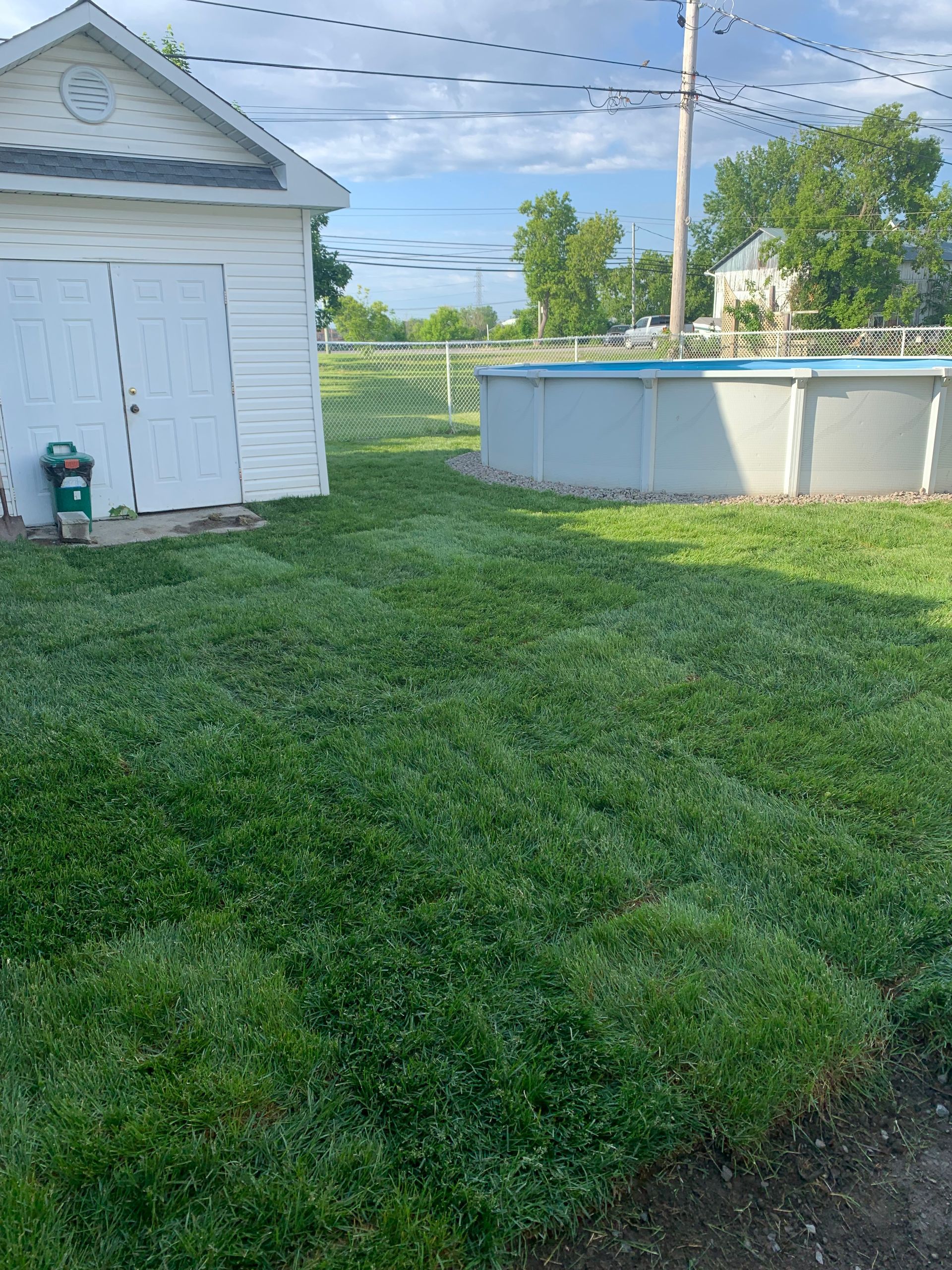 Il y a une piscine dans la cour à côté d'un cabanon.