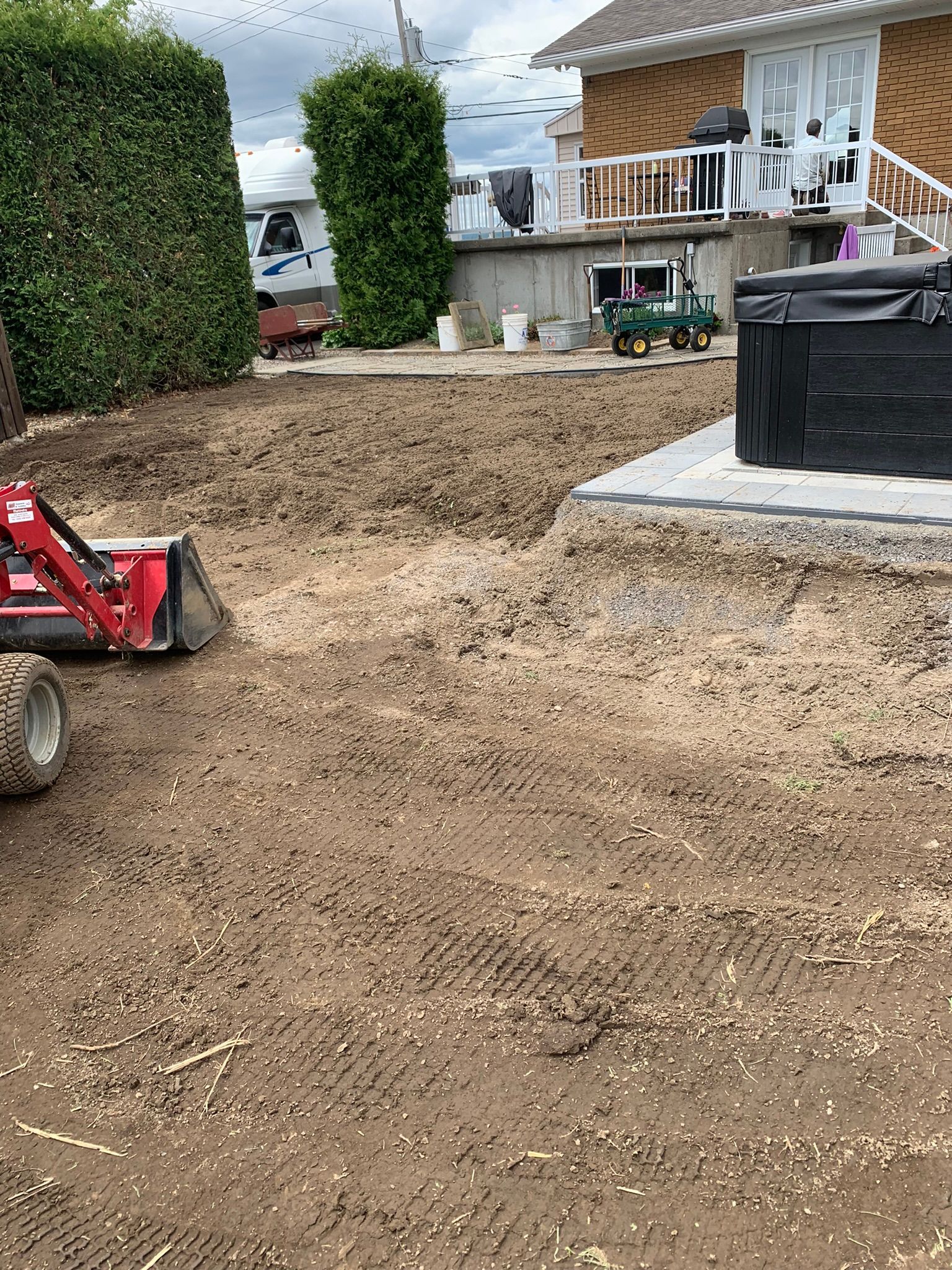 Un bulldozer déplace de la terre dans une cour devant une maison.