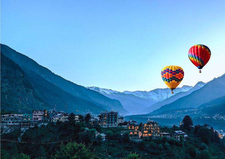 Two Hot Air Balloons Flying Over the City on Mountain Range