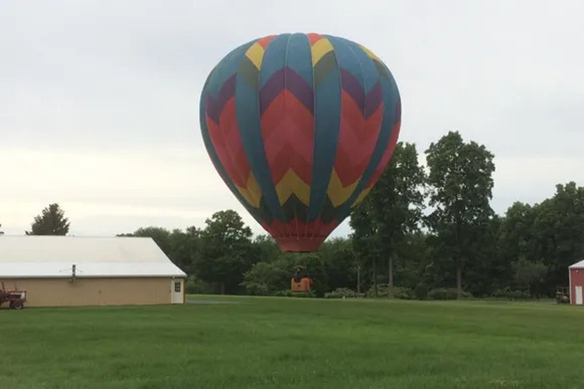 Colorful Hot Air Balloon Flying Over the Grassy Field