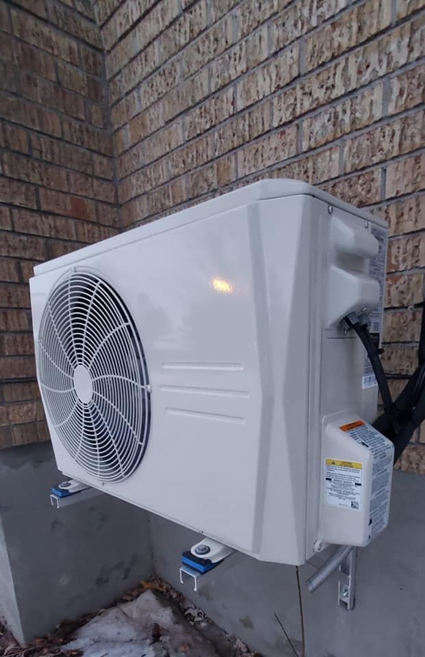 Un climatiseur blanc est monté sur le côté d'un bâtiment en briques.