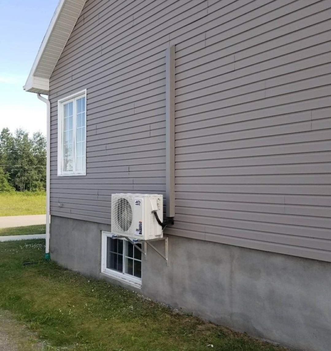 Une maison avec une fenêtre et un climatiseur sur le côté.