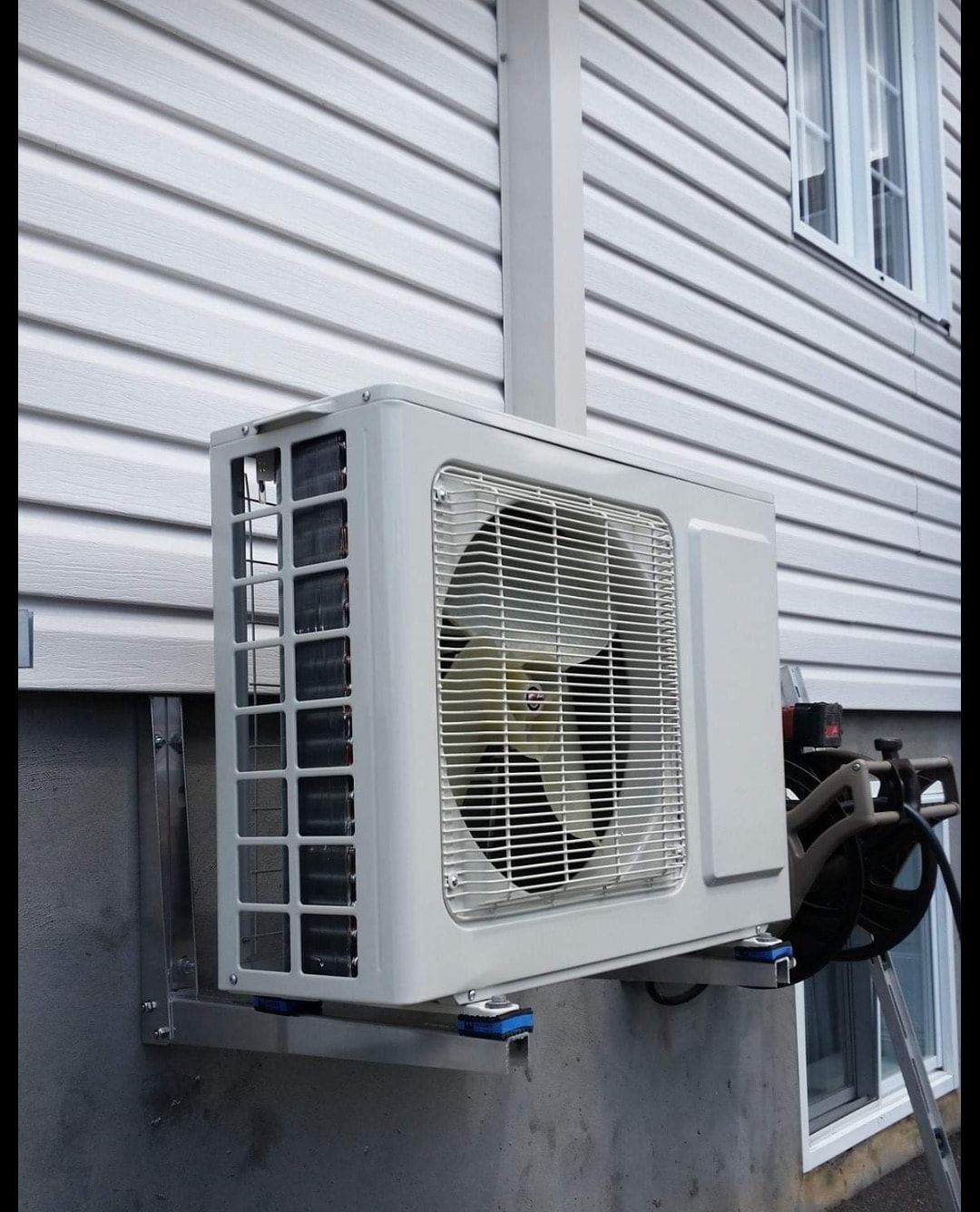 Un climatiseur blanc est monté sur le côté d'une maison