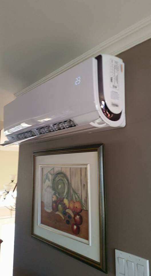Un climatiseur blanc est accroché au mur à côté d'un tableau encadré.