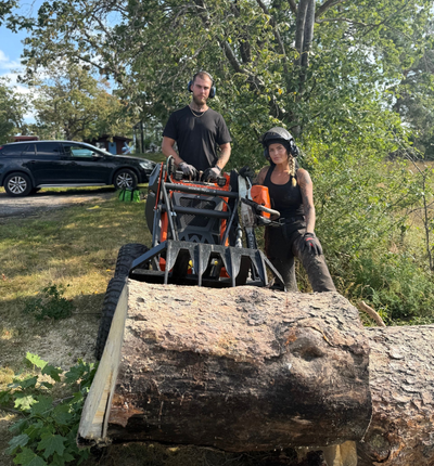 En person sågar en stock med en motorsåg.