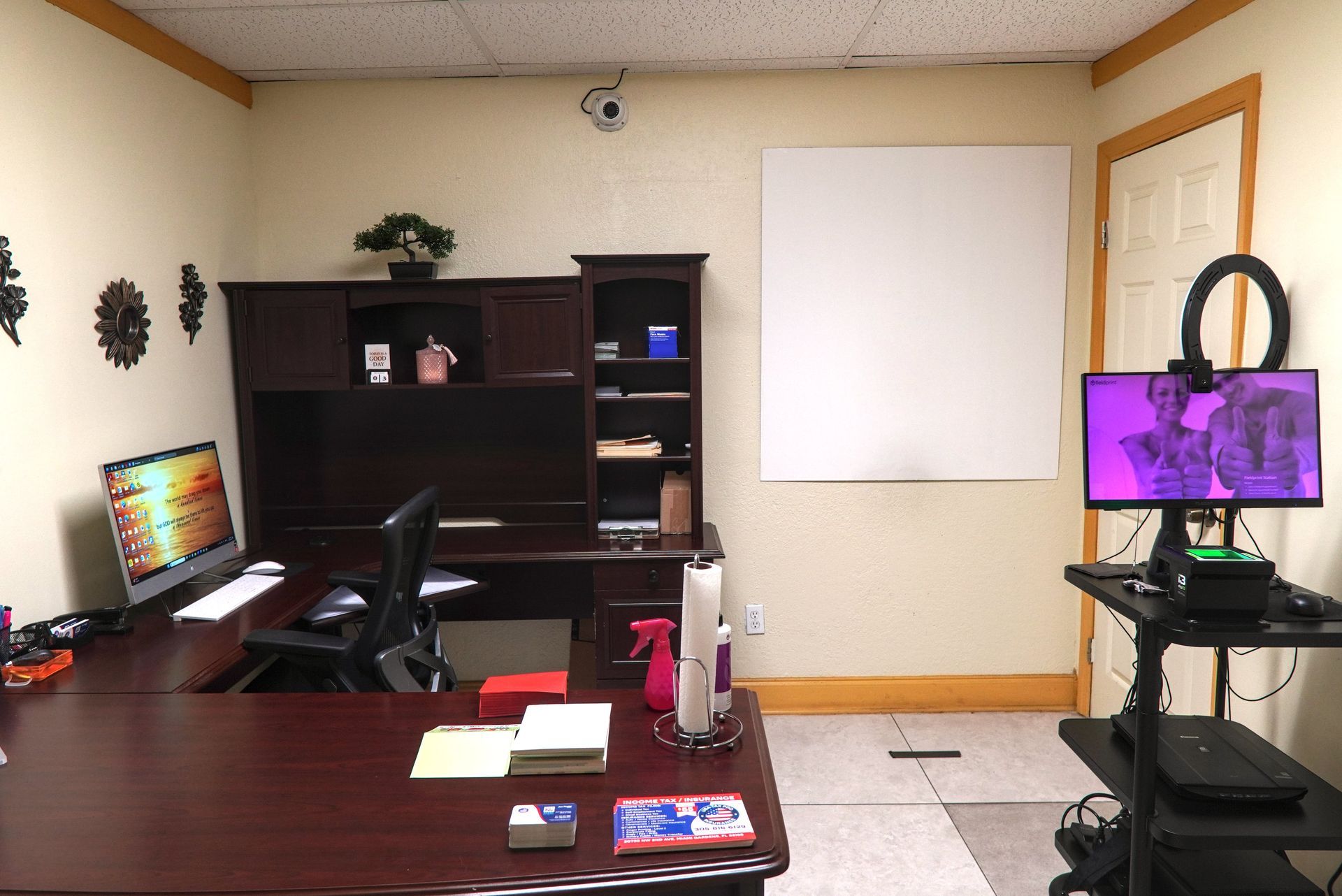 Office with desk, computer, whiteboard, and video recording setup.