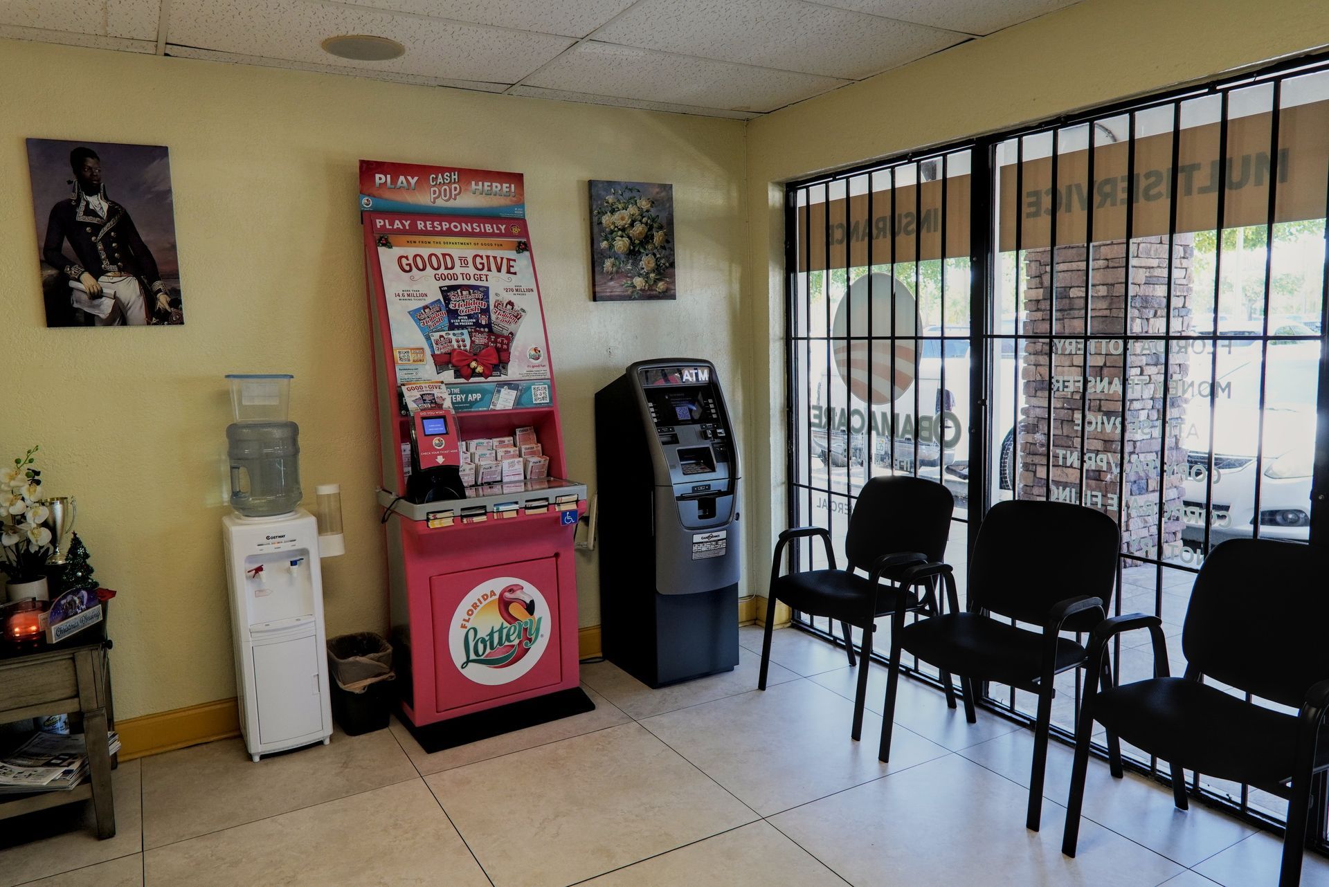 Waiting room with chairs, a water cooler, vending machine, and ATM. A painting hangs on the wall.
