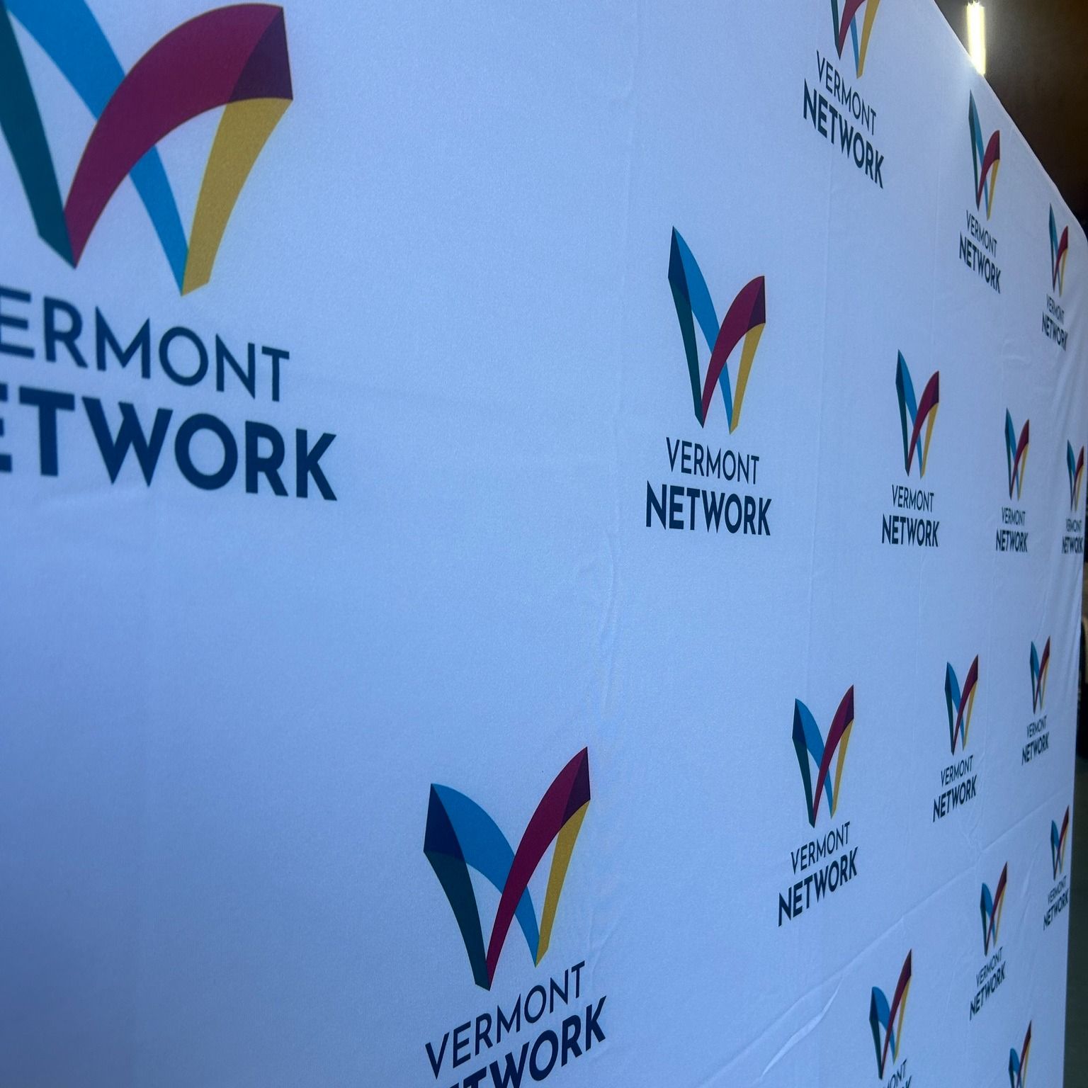 Vermont Network backdrop with logo repeated on a white background.