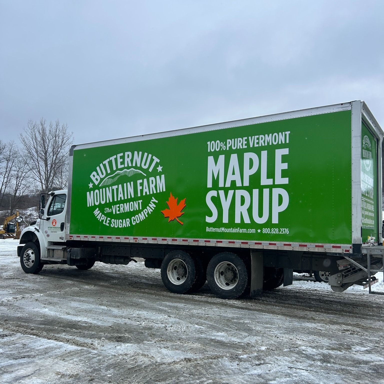 Green truck with "Butternut Mountain Farm Maple Syrup" graphic on side, parked in snowy lot.