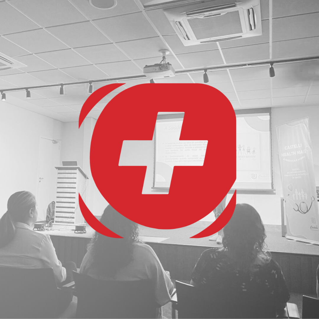 Um grupo de pessoas está sentado em uma sala de aula com uma cruz vermelha no meio