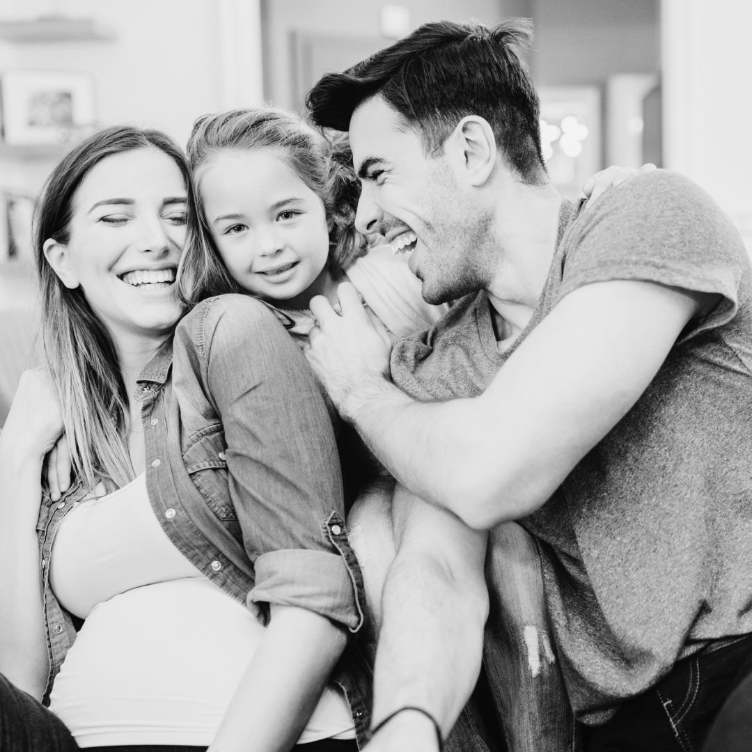Uma foto em preto e branco de uma família sentada em um sofá.