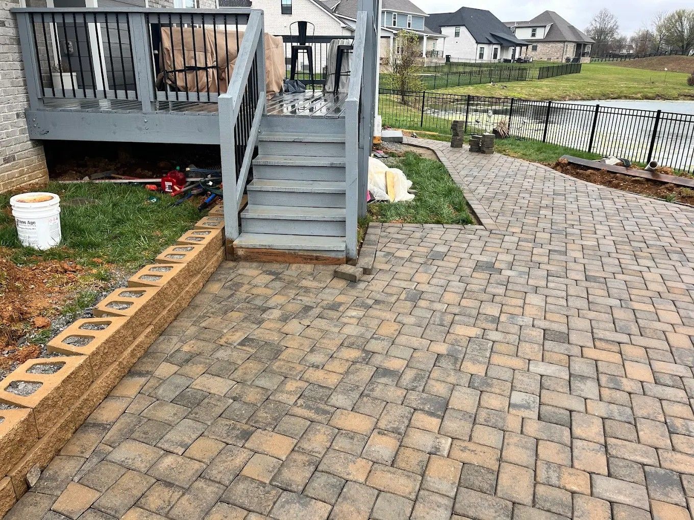 A patio with stairs leading up to a deck in a backyard.