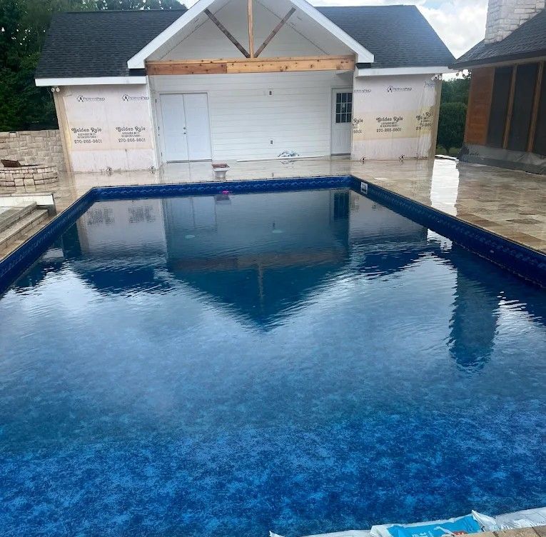 A large swimming pool with a house in the background