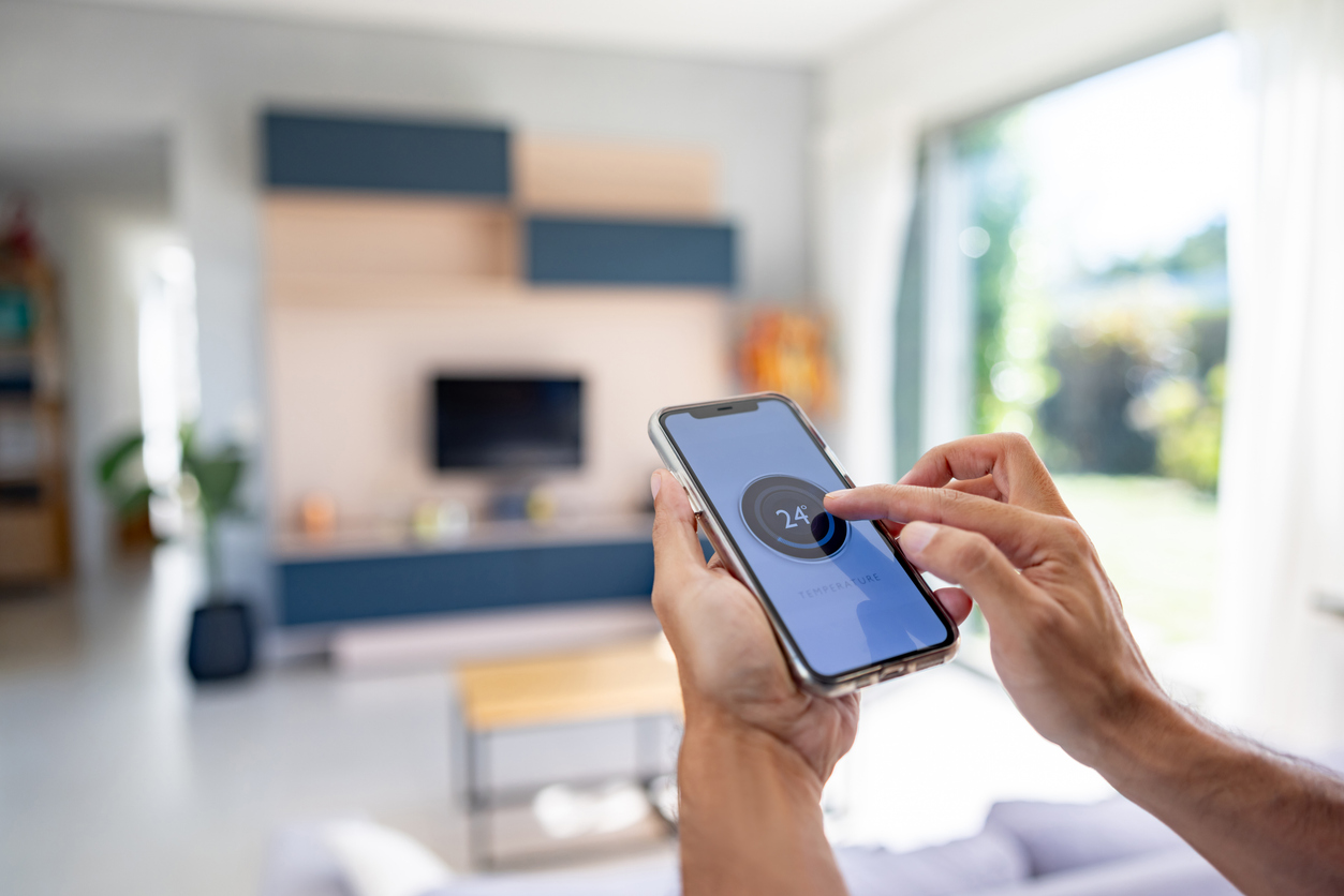 Person using a smartphone to control smart home features in a living room.