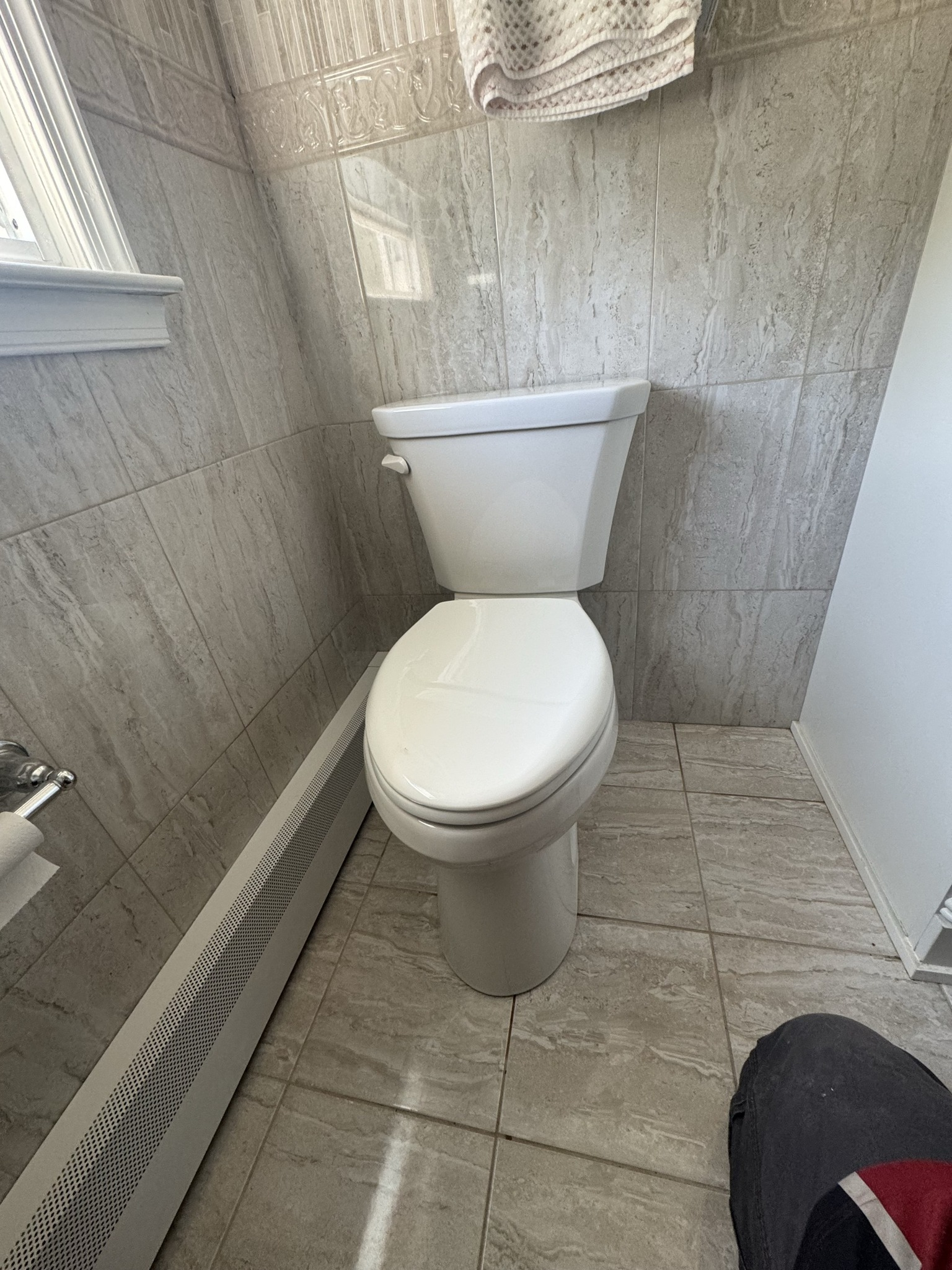 Toilet in a bathroom with gray tiled walls and floor.