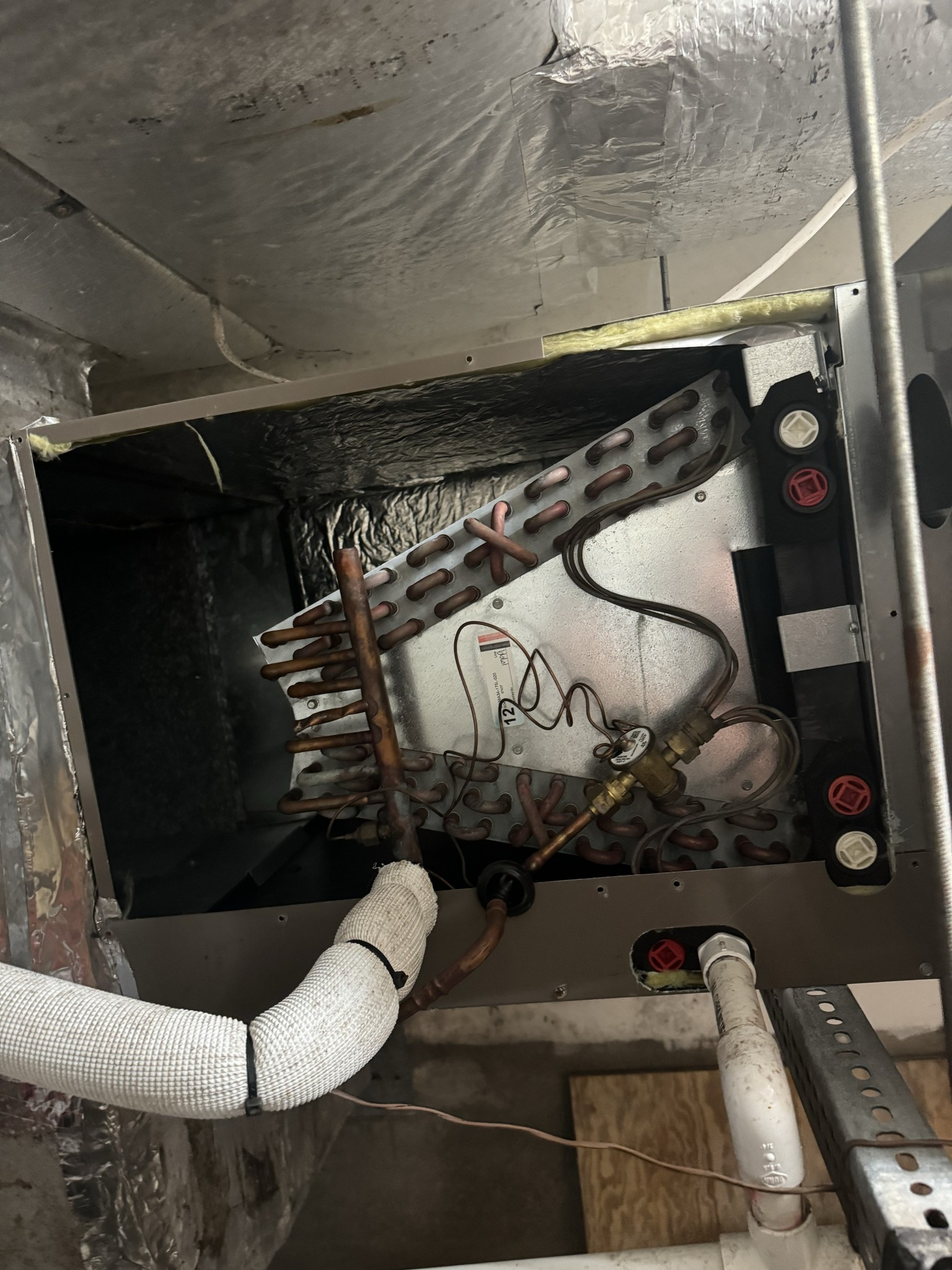 HVAC unit interior. Silver metal components with copper tubing, insulation, and electrical wiring.