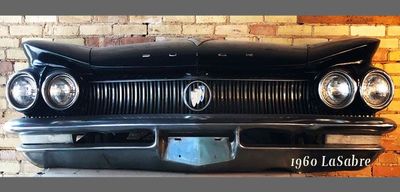 A 1960 buick la sabre is hanging on a brick wall