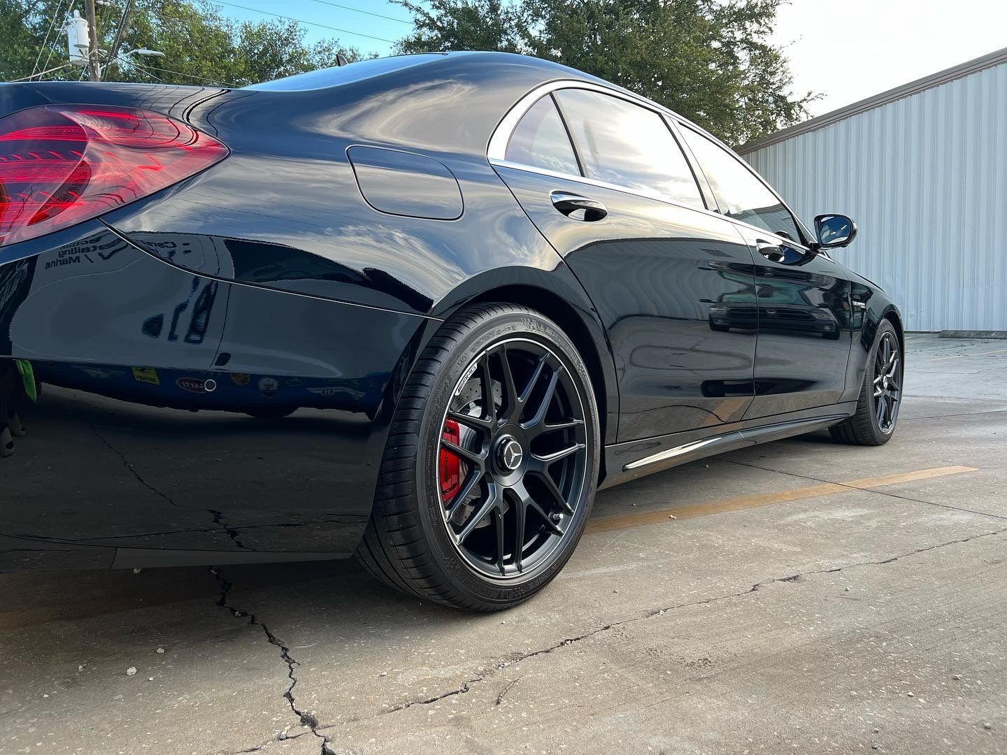 A black car with red brake calipers is parked in a parking lot.
