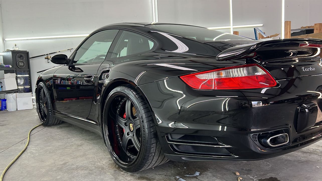 A black porsche turbo is sitting in a garage.