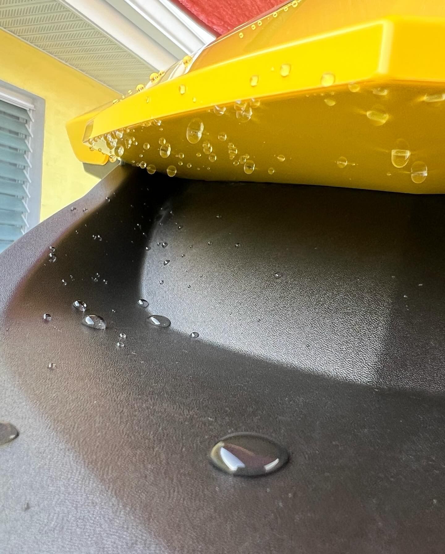 A close up of a yellow object with water drops on it