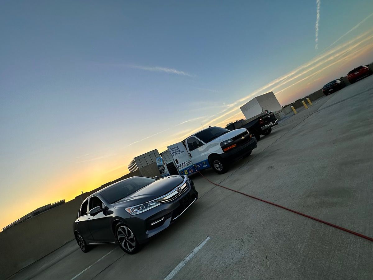 A row of cars are parked in a parking lot at sunset