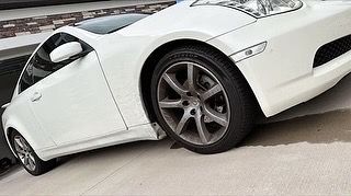 A white sports car is sitting on the side of the road.