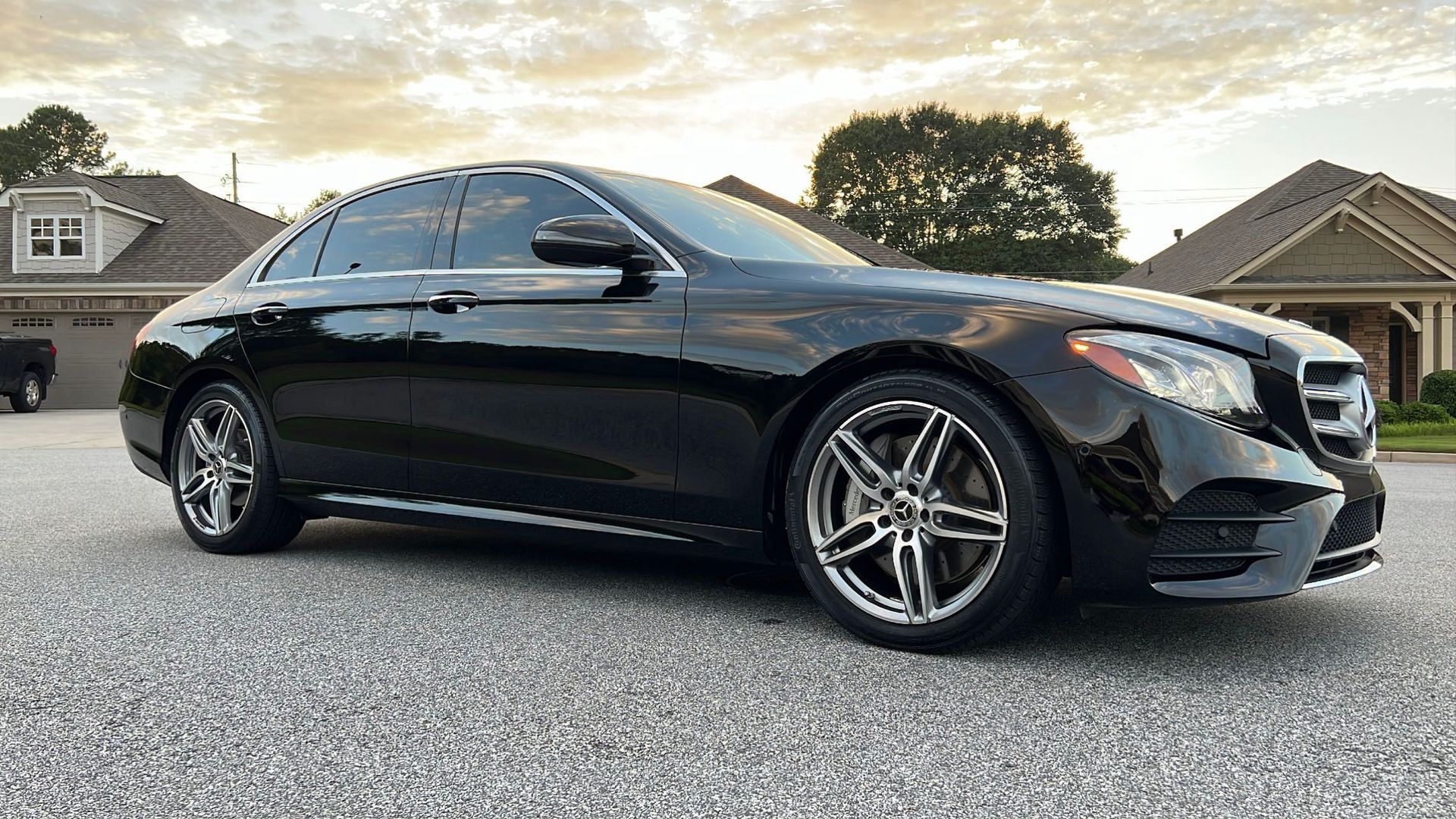 A black mercedes benz e class is parked in a driveway in front of a house.