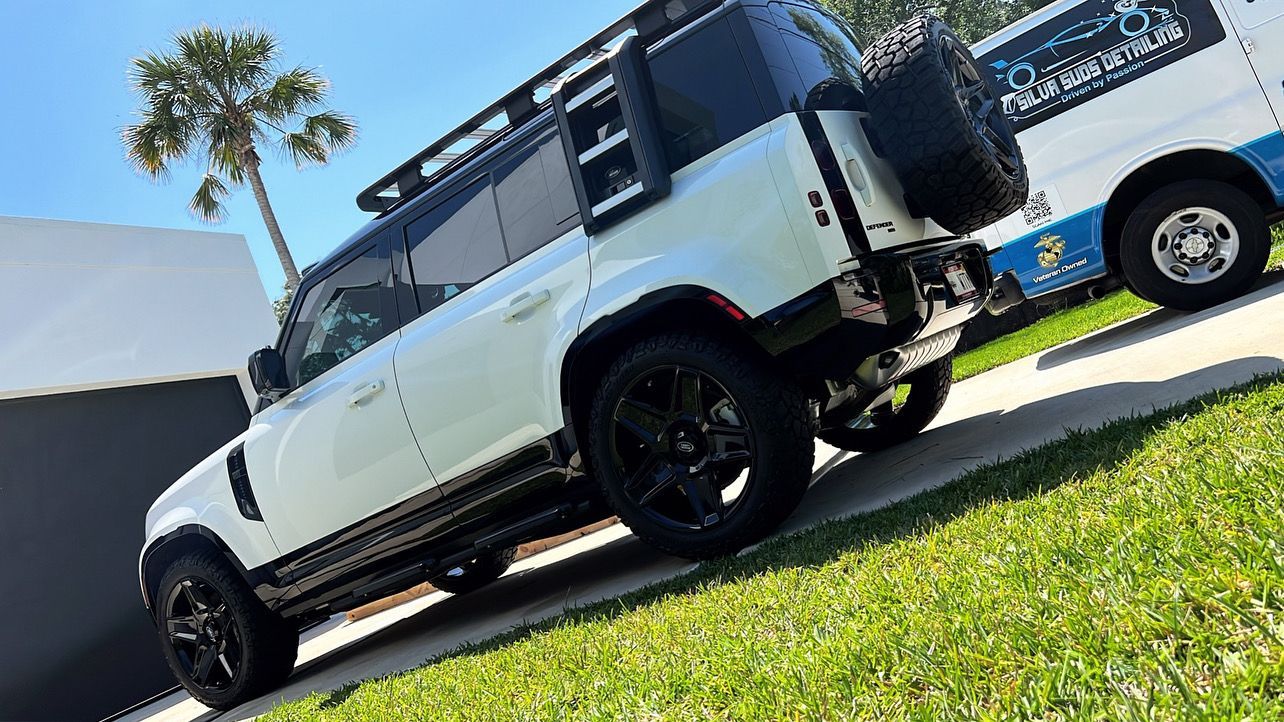 A white suv is parked on the side of the road next to a white van.